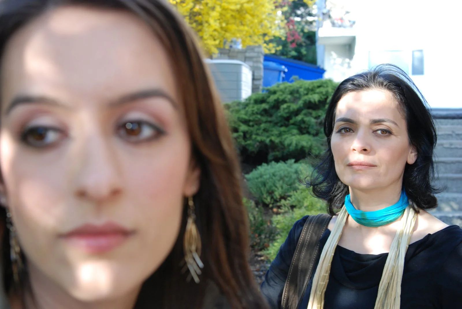 Two women in close-up, one looking past the camera, the other turned away.